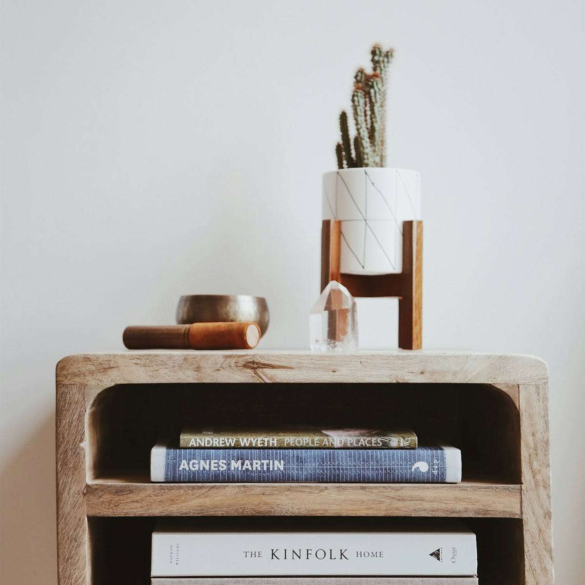 Rounded solid wood bedside table with open shelves holding books
